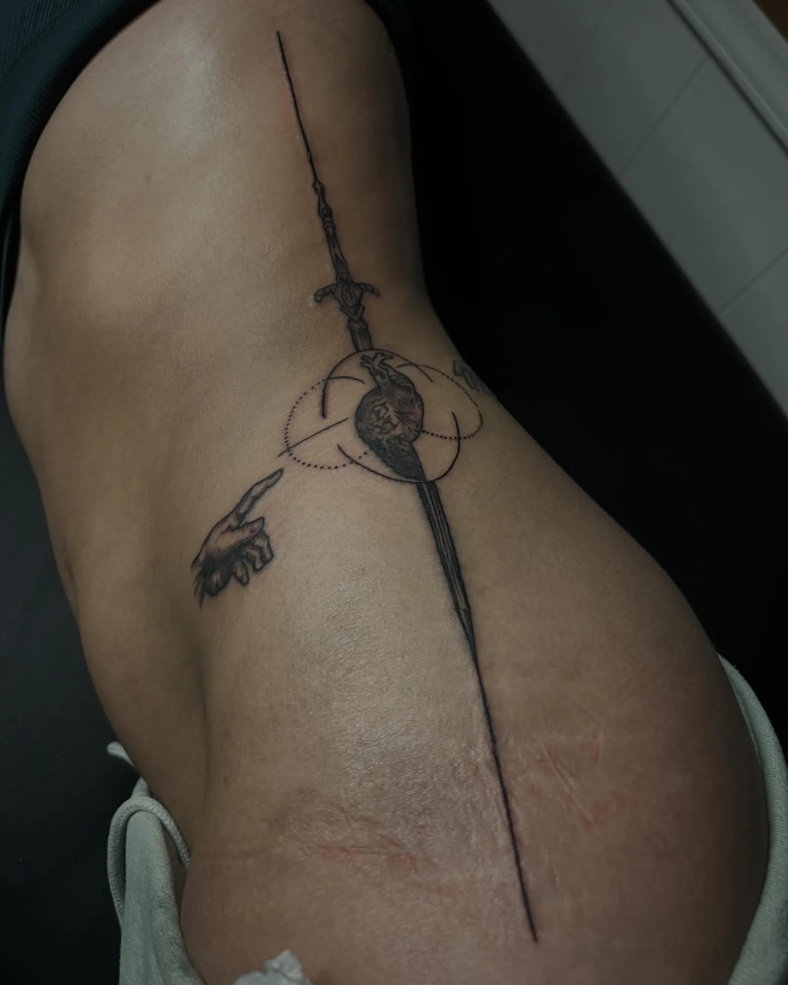 Fine line dagger and ornamental sigil tattoo running down the rib cage by Creative Tat at Shadow Studio Charlotte