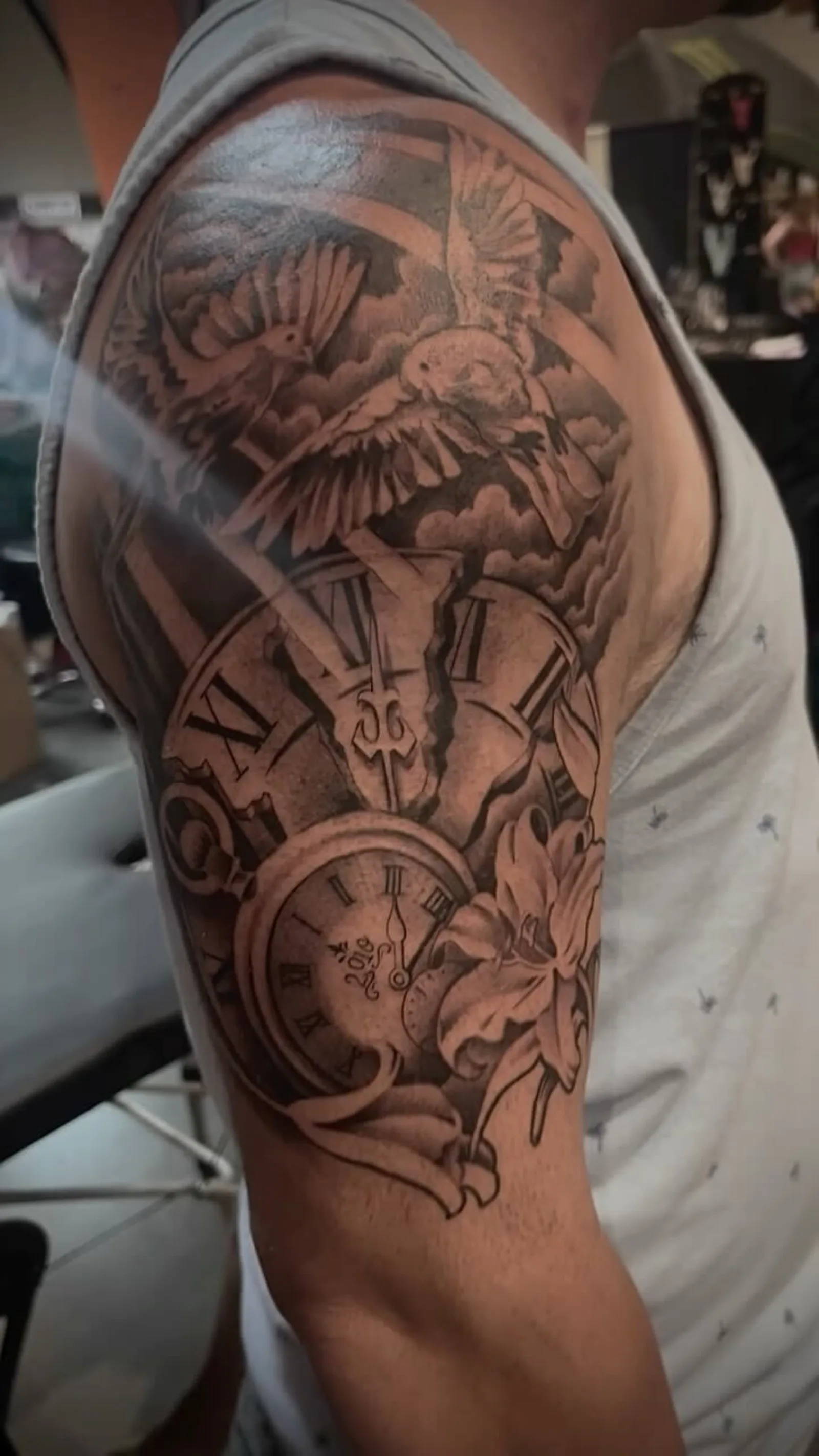 Black and grey upper-arm sleeve of a dove with pocket watch and lilies by Creative Tat at Shadow Studio Charlotte