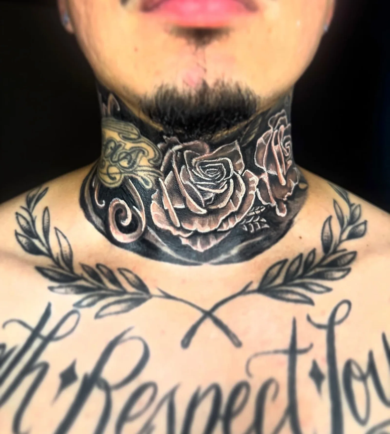 Black and grey neck tattoo of three roses inside a laurel wreath above the chest by Fresiato at Shadow Studio Charlotte