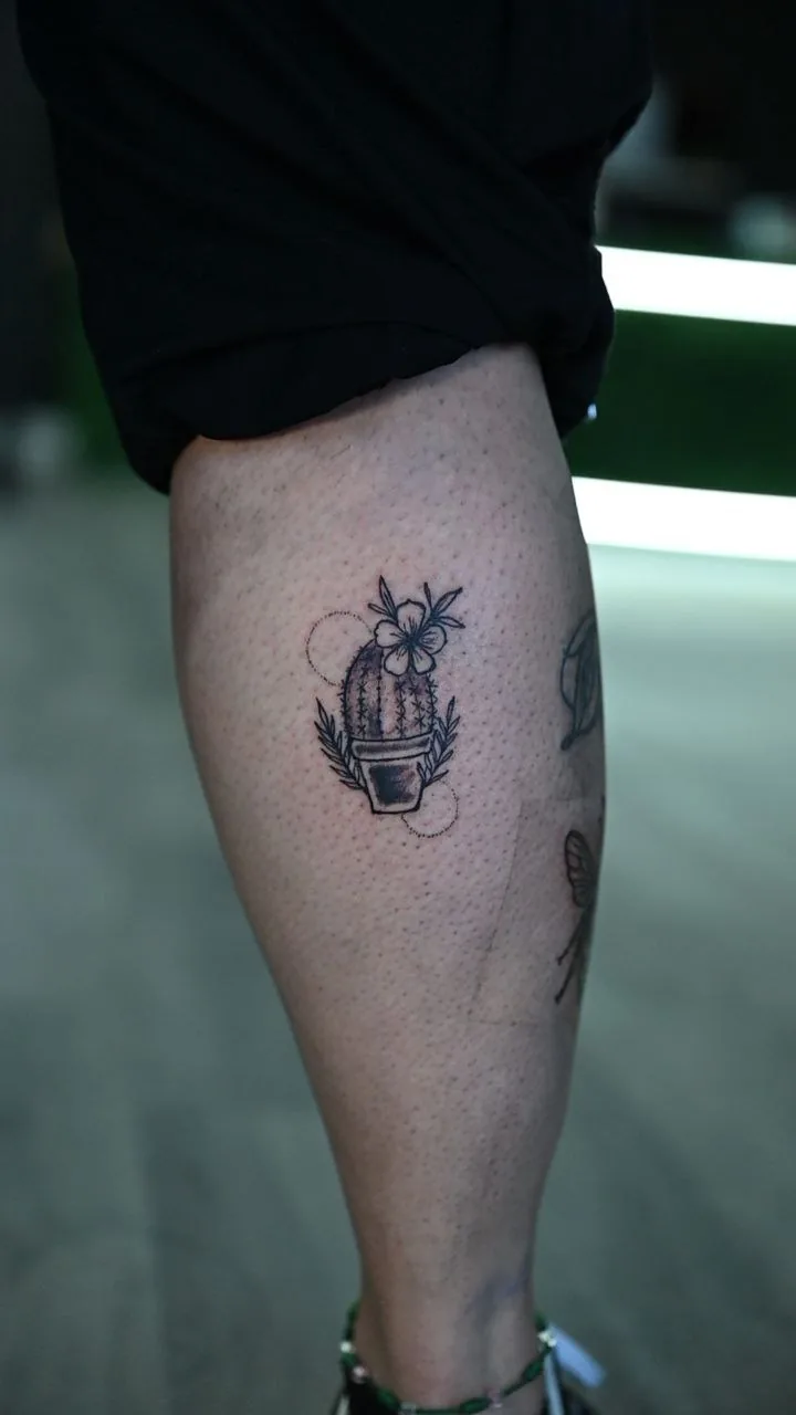Fine line single-needle calf tattoo of a small potted cactus by Inked Bites at Shadow Studio Charlotte