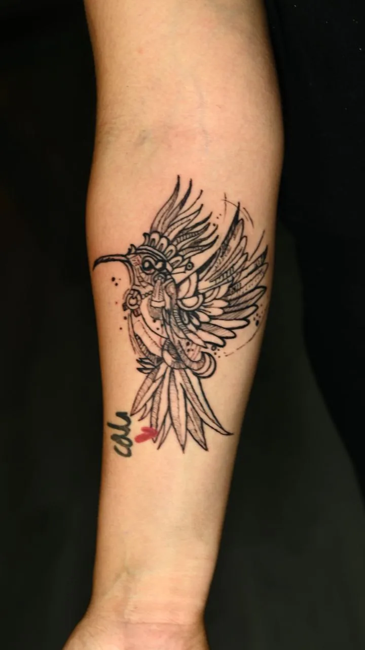 Fine line hummingbird forearm tattoo with red wing accents and the word "ash" by Inked Bites at Shadow Studio Charlotte