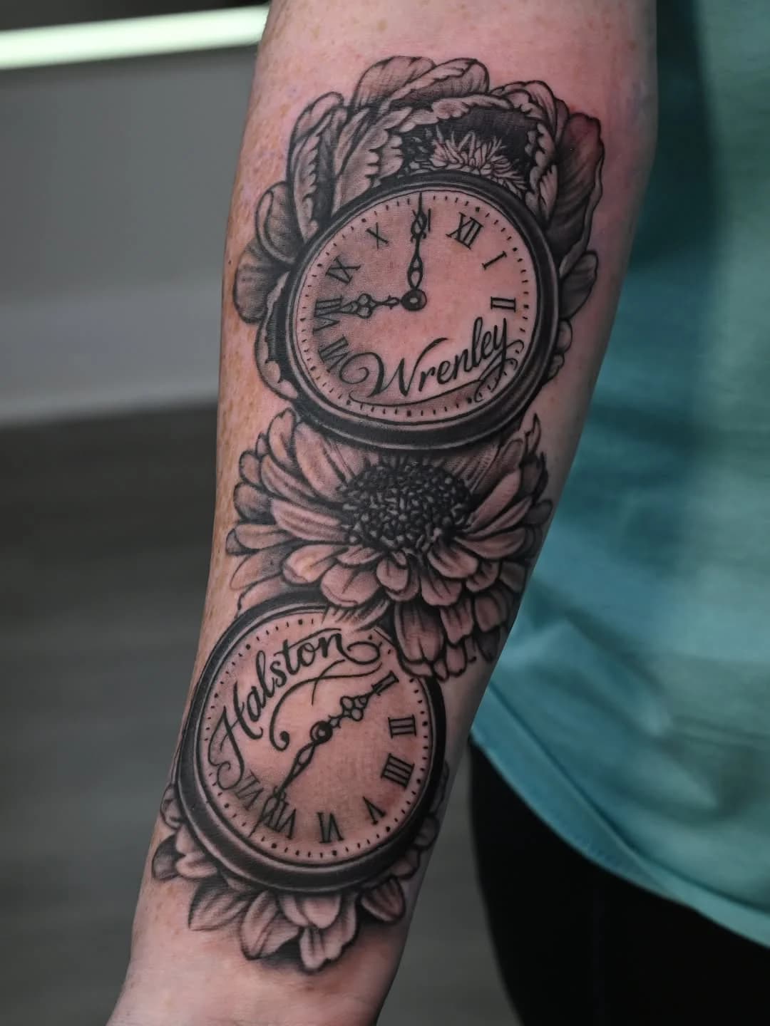 Black and grey neo-traditional forearm tattoo of two pocket watches and a chrysanthemum with the names "Wrenley" and "Halston" by Joel at Shadow Studio Charlotte
