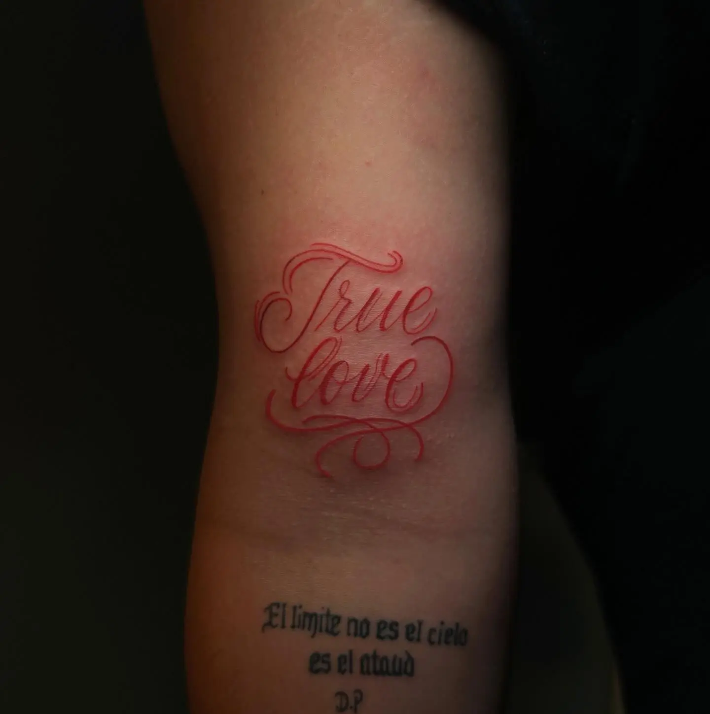 Red-ink "True Love" script tattoo on the inner arm by Venus at Shadow Studio Charlotte