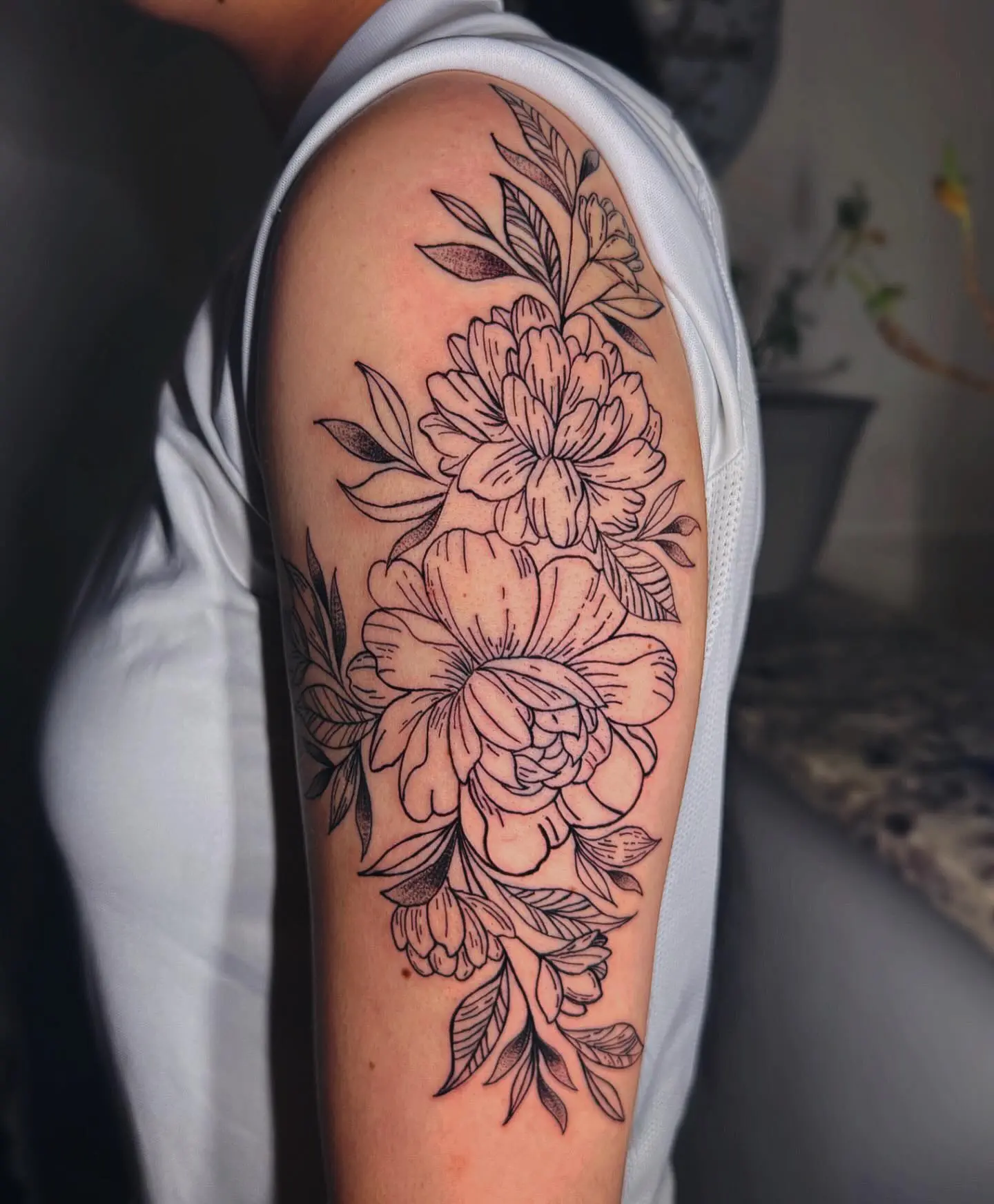 Black and grey fine-line peony floral upper-arm tattoo by Venus at Shadow Studio Charlotte