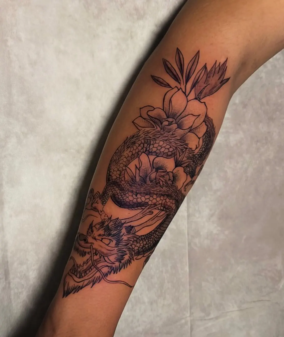 Fine line forearm dragon tattoo with floral accents by Venus at Shadow Studio Charlotte